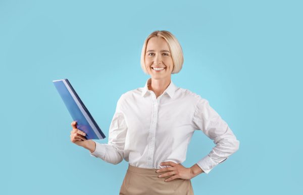 Portrait of positive female entrepreneur in office wear holding folder with documents over blue