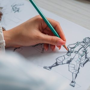 selective focus of illustrator drawing cartoon character on paper