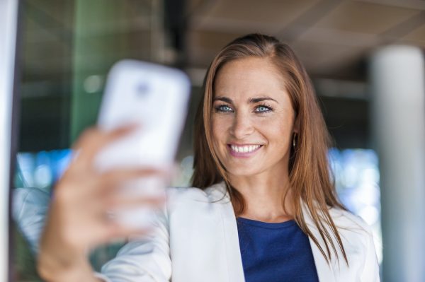 Smiling brunette woman holding cell phone