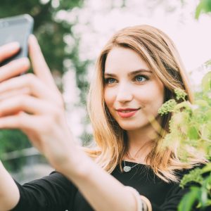 Young woman using smartphone taking selfie