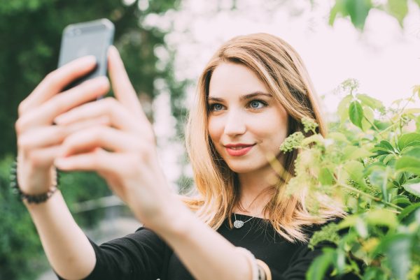 Young woman using smartphone taking selfie